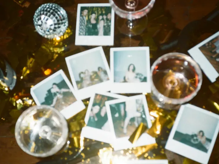 Polaroid prints of party guests scattered on a table with glasses